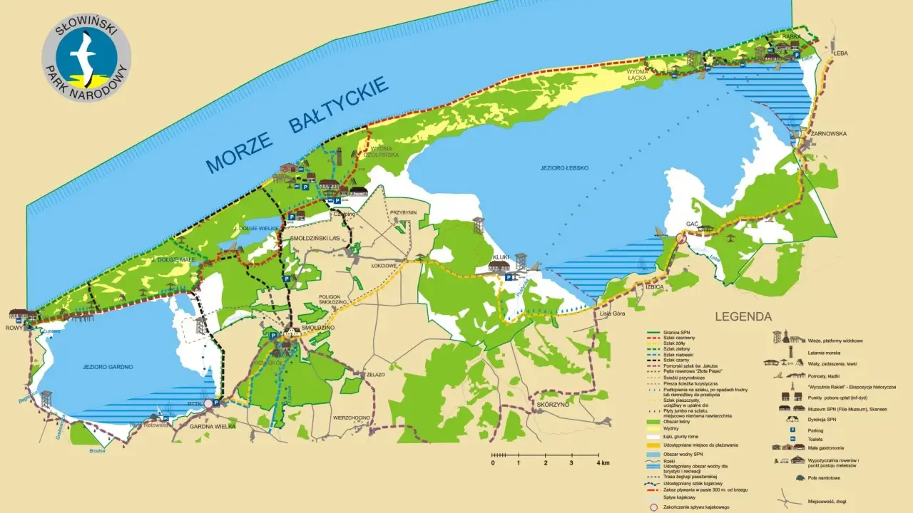 Mapa turystyczna Słowińskiego Parku Narodowego z zaznaczonymi szlakami, jeziorami, wydmami i miejscowościami.
