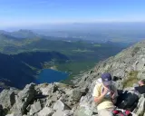 Widok na Tatry z żlebu Kulczyńskiego. W dole jezioro, na pierwszym planie odpoczywający turyści.