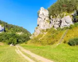 Wspinacze na skalnej ścianie w Dolinkach Krakowskich. Kręta ścieżka prowadzi przez zielone wzgórza.