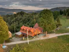 Malowniczy dom z czerwonym dachem w otoczeniu zielonych wzgórz. Idealne miejsce na agroturystykę w Pieninach, gdzie można odpocząć od zgiełku.