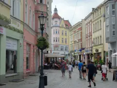 Spacer po urokliwej uliczce z kolorowymi kamienicami, idealne miejsce na zielona góra atrakcje na weekend. Ludzie spacerują, siedzą w kawiarniach.